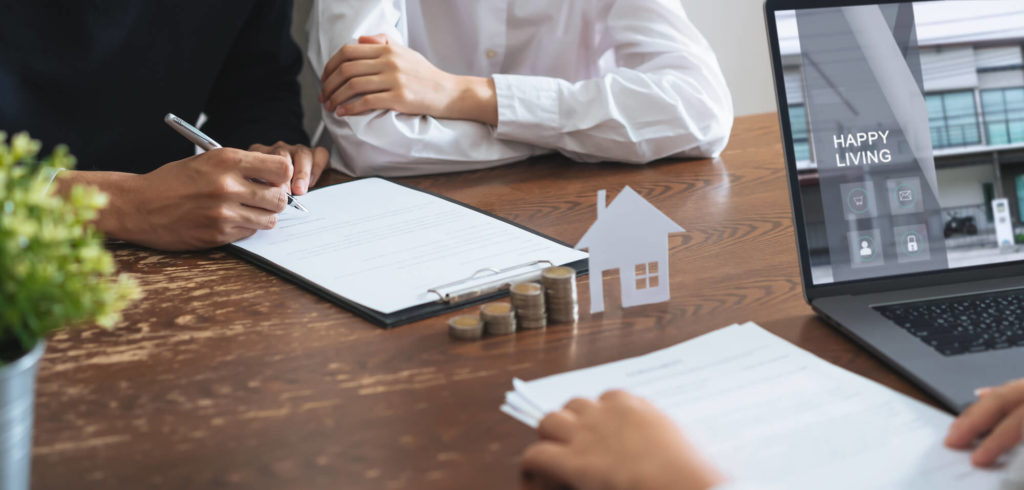 Image showing a couple signing real estate documents with money in front of them.