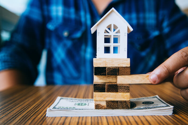 Image of a wooden home and a stack of cash representing home value.