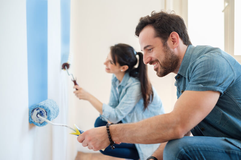 Image of a couple painting the walls in their home.