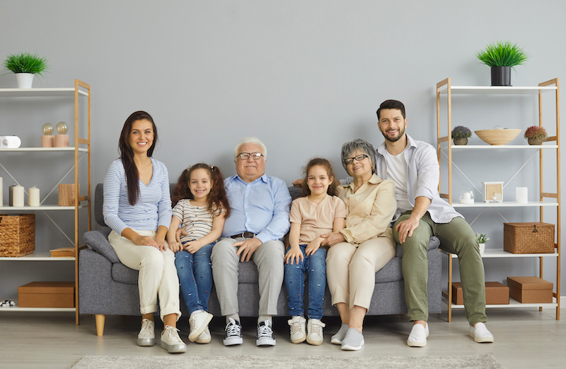 Portrait of happy extended multigenerational family all together on sofa at home.