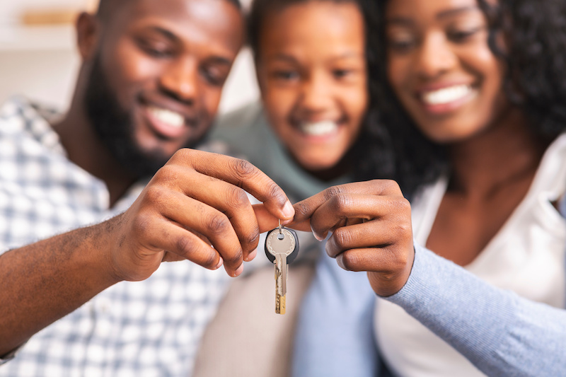 Happy family with daughter holding keys from their new home, selective focus on hands, closeup.