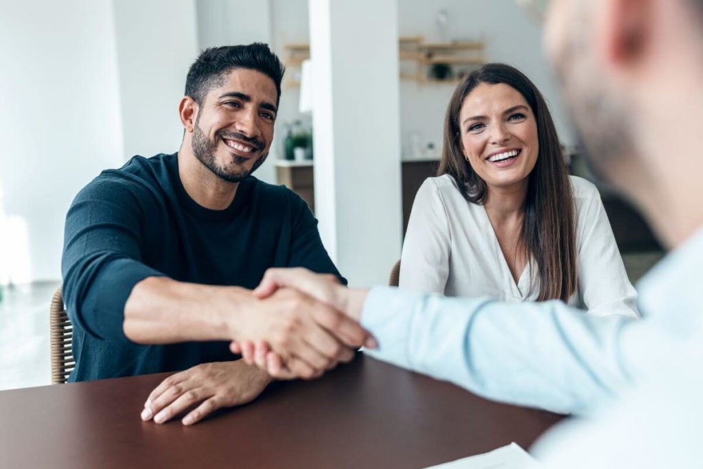 couple shaking hands with real estate agent