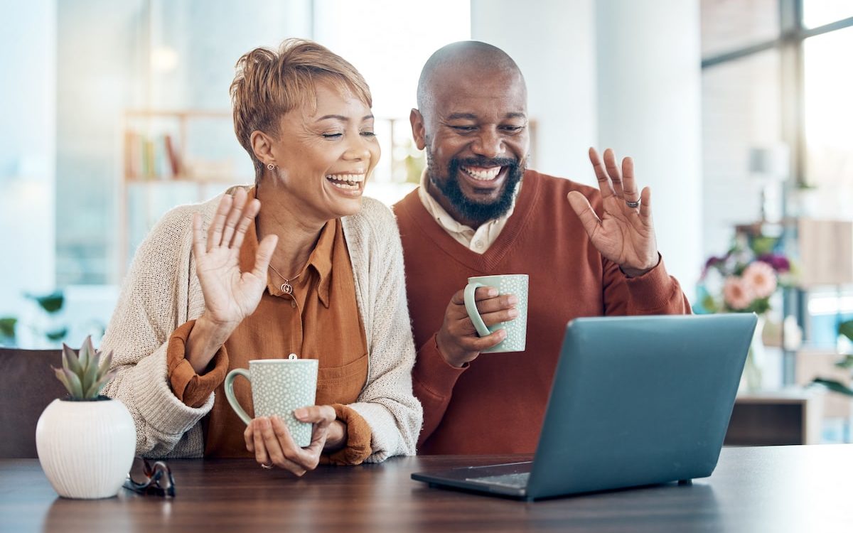 couple waving at laptop on virtual meeting