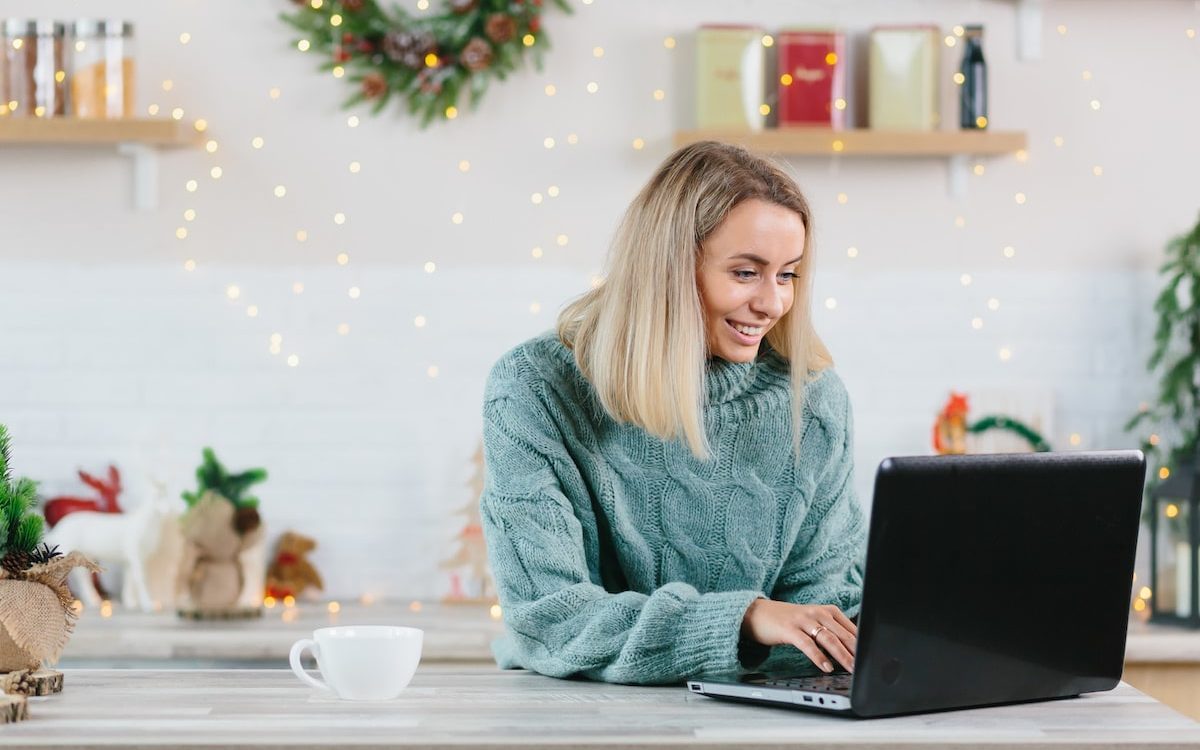 woman on laptop with home decorated for the holidays