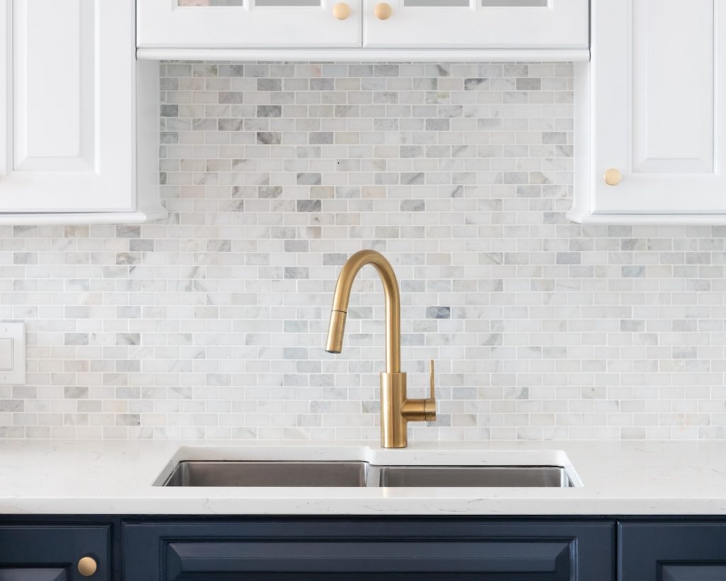closeup of gold kitchen faucet and blue cabinets