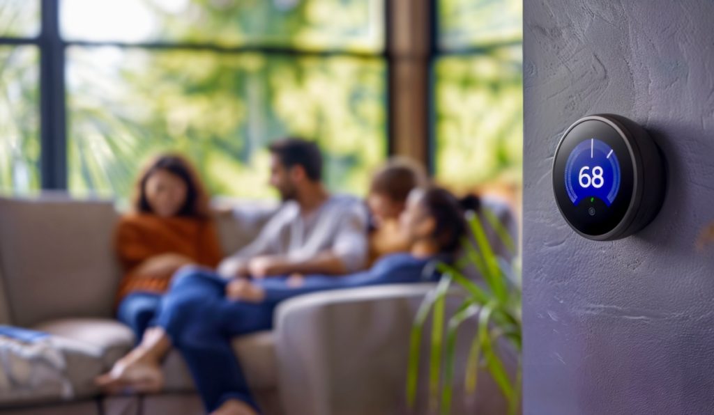 Closeup of a smart thermostat with happy family on couch