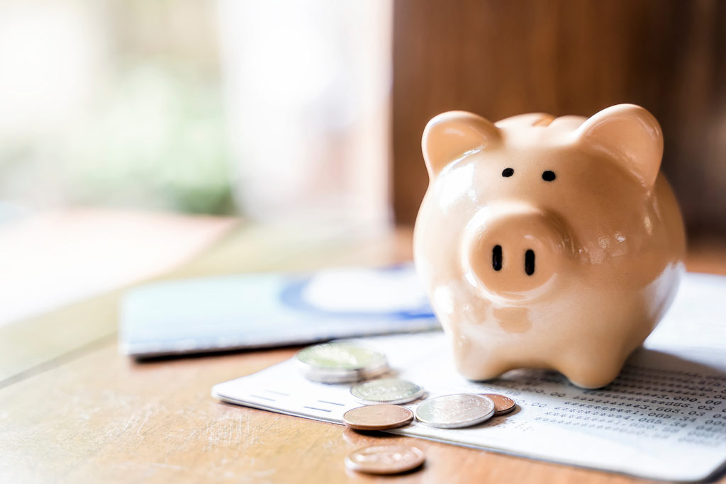 Pink piggy bank with coins scattered around 