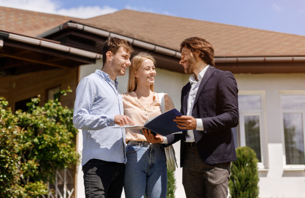 a young caucasian couple touring a home with the help of their realtor